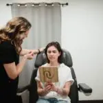 An esthetician consults a client holding a mirror in a medical spa treatment room.